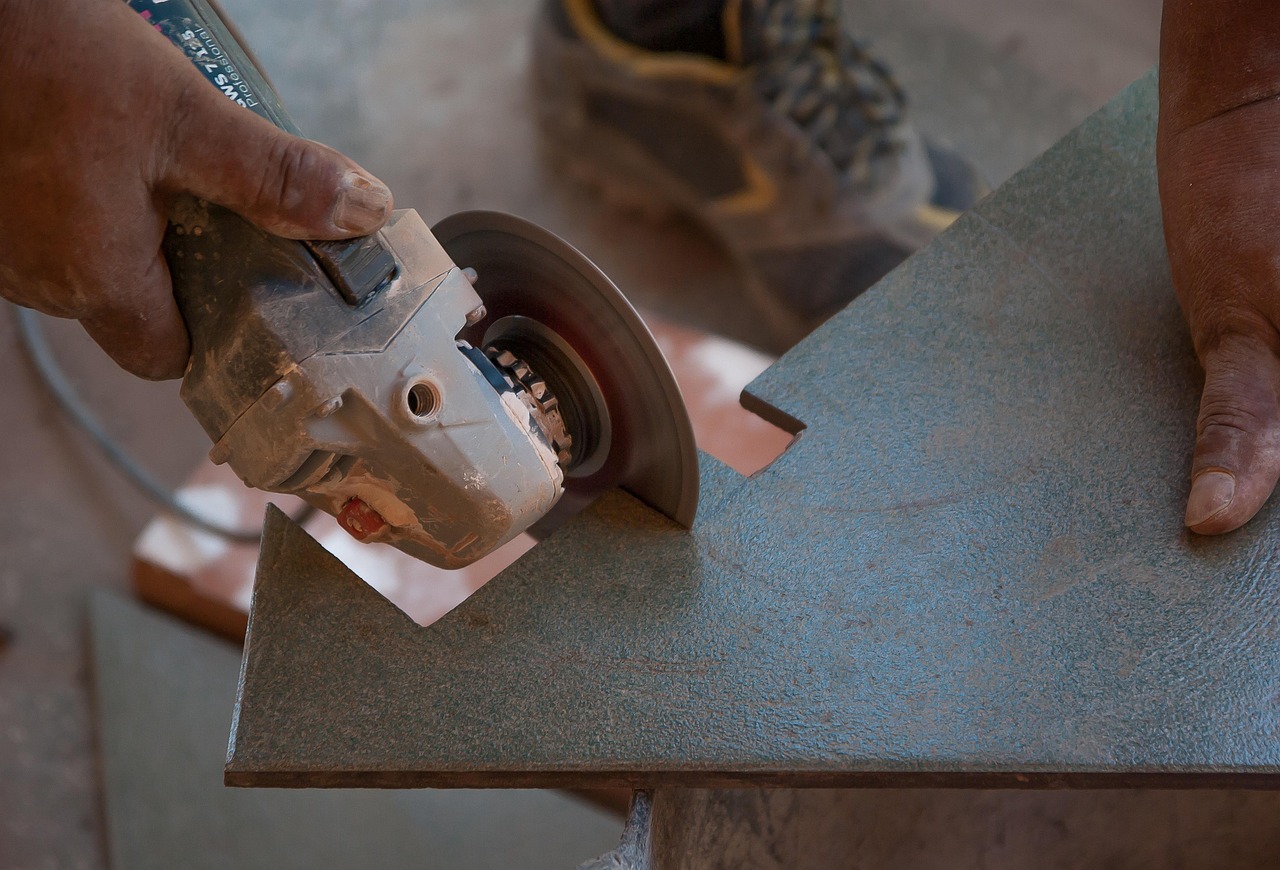 Hands guiding an angle grinder across a hard surface